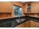 Gourmet kitchen featuring granite countertops, natural wood cabinets, and stainless steel sink at 1521 San Helen Dr, Dunedin, FL 34698