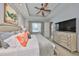 The main bedroom features a tray ceiling, ceiling fan, a dresser with a tv and a comfortable bed at 1647 Emerald Dunes Dr, Sun City Center, FL 33573