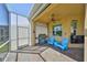 Screened patio with an outdoor kitchen, fan, roll-down shade, blue chairs, and tile flooring at 1647 Emerald Dunes Dr, Sun City Center, FL 33573