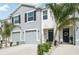 Beautiful townhome featuring a gray garage, contrasting white stucco, and tropical palm tree landscaping at 16646 Maude Dr, Wimauma, FL 33598
