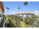 Balcony view showcasing tropical landscaping, ocean views, and nearby buildings at 254 Seagate Ct, Dunedin, FL 34698