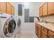 Bright laundry room equipped with a front-loading washer/dryer and sink with wood cabinets at 254 Seagate Ct, Dunedin, FL 34698