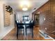 Open dining area with stylish lighting, hardwood floors, and seamless transition to kitchen with brick accent wall at 3219 Spanish Moss Ln, Palm Harbor, FL 34684