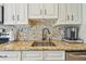 Updated kitchen with granite countertops, stainless steel sink, mosaic backsplash, and white cabinetry at 3632 Pine Cone Cir, Clearwater, FL 33760