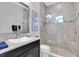 Bright bathroom featuring a walk-in shower with decorative tile, a wide mirror and a modern sink with a granite countertop at 4681 Night Star Trl, Odessa, FL 33556