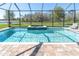 Sparkling screened-in pool with an attached jacuzzi, patio, and lush greenery beyond at 4681 Night Star Trl, Odessa, FL 33556