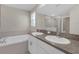 Bathroom with double sinks, a large mirror, and a soaking tub with a tiled shower at 7229 Spring Snowflake Ave, Tampa, FL 33619