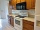Corner view of kitchen with white electric range, microwave, and wood cabinets at 2105 Haydon Ct, Brandon, FL 33511