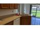 Corner kitchen sink featuring wood cabinets, light countertop, and white dishwasher at 2105 Haydon Ct, Brandon, FL 33511