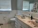 Bathroom with a dual sink vanity, mirror, toilet, and a tiled shower with a curtain at 10126 Bahama Ct, Seminole, FL 33776