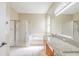 Bathroom with dual sinks, granite countertops, glass-enclosed shower, and a soaking tub at 10641 Firebrick Ct, Trinity, FL 34655