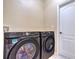 A modern laundry room features a full-size Samsung washer and dryer, and a white door with dark handle at 10641 Firebrick Ct, Trinity, FL 34655