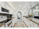 Well-lit kitchen featuring stainless steel appliances, dark backsplash, granite countertops, and white cabinetry at 13553 Landers Dr, Hudson, FL 34667