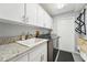 Functional laundry room featuring a utility sink, granite counters, and storage cabinets for convenience at 13553 Landers Dr, Hudson, FL 34667