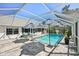 Relaxing screened-in pool area with stylish patio, umbrellas, and lounge chairs offers a private outdoor oasis at 13553 Landers Dr, Hudson, FL 34667