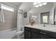 Bathroom features a shower over tub, neutral tile, a mirror over vanity, and ample lighting at 15401 Caravan Ave, Odessa, FL 33556