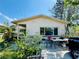 Street view of a single-story home featuring large windows and a light-colored exterior with some outdoor furniture at 1800 New Hampshire Ne Ave, St Petersburg, FL 33703