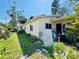 Side view of a one-story home, displaying a light-colored exterior and some mature landscaping in need of TLC at 1800 New Hampshire Ne Ave, St Petersburg, FL 33703