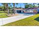 Charming home showcasing a well-manicured lawn, palm trees, and a long driveway leading to a two-car garage at 2096 Church Creek Pt, Largo, FL 33774