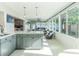 Bright kitchen with gray cabinets, white countertops, and modern lighting, flowing into a sunroom with lots of windows at 2096 Church Creek Pt, Largo, FL 33774