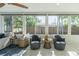 Bright sunroom features cozy seating, neutral decor, and large windows overlooking a fenced yard at 2096 Church Creek Pt, Largo, FL 33774