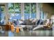 Sunroom featuring a comfortable gray sectional sofa adorned with stylish pillows, framed by large windows offering verdant views at 2096 Church Creek Pt, Largo, FL 33774