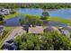 Aerial view of a home with a nearby lake, surrounded by lush greenery and mature trees at 2199 Springrain Dr, Clearwater, FL 33763
