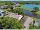 Aerial view of a house located next to a picturesque lake, framed by mature trees and green lawns at 2199 Springrain Dr, Clearwater, FL 33763