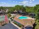 Aerial view showcasing a community pool, tennis court, and clubhouse surrounded by lush trees in a neighborhood setting at 2199 Springrain Dr, Clearwater, FL 33763