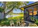 Waterfront back porch view with two ornamental chairs and lush landscaping at 2199 Springrain Dr, Clearwater, FL 33763