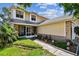 Charming two-story home featuring yellow siding, a screened-in porch, and landscaped front yard at 2199 Springrain Dr, Clearwater, FL 33763