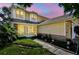 Charming two-story home featuring yellow siding, a screened-in porch, and landscaped front yard at 2199 Springrain Dr, Clearwater, FL 33763