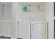 Efficient laundry room with washer, dryer, and storage shelves for supplies at 2572 Forest Run Ct, Clearwater, FL 33761