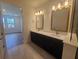Elegant bathroom featuring double sinks, quartz countertops, sleek black cabinetry, and gold fixtures at 2832 Marrakesh Ln, Sarasota, FL 34234