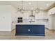 Modern kitchen features white cabinets, stylish light fixtures, stainless steel appliances, and a large island at 2832 Marrakesh Ln, Sarasota, FL 34234
