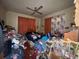 Cluttered bedroom features a ceiling fan, curtains, and visible signs of deferred maintenance at 3106 E 25Th Ave, Tampa, FL 33605
