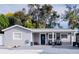 Charming single-story home with blue front door, manicured lawn and welcoming front porch with chairs at 314 E Althea Ave, Tampa, FL 33612