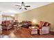 Warm living room with hardwood floors, leather furniture, ceiling fan, and an open transition to the dining area at 31833 Turkeyhill Dr, Wesley Chapel, FL 33543