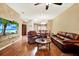 Cozy living room with hardwood floors, leather furniture, a ceiling fan, and an open floor plan at 31833 Turkeyhill Dr, Wesley Chapel, FL 33543