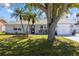 Charming single-story home featuring well-manicured lawn, fresh gray paint, and mature landscaping at 3352 Honeymoon Ln, Holiday, FL 34691