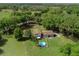 Aerial view of a cozy home with an above-ground pool, surrounded by lush greenery and a pond at 4902 Five Acre Rd, Plant City, FL 33565