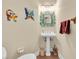 Half bathroom with pedestal sink, decorative mirror and colorful butterfly and lizard wall hangings at 4965 Anniston Cir, Tampa, FL 33647