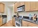 Modern kitchen featuring stainless steel appliances and wood cabinets, a dishwasher, and black countertops at 4965 Anniston Cir, Tampa, FL 33647