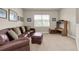 Cozy living room featuring a leather sectional, ottoman, neutral carpet, and a bright window, perfect for relaxation at 4965 Anniston Cir, Tampa, FL 33647