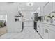 Modern all-white kitchen featuring marble floors, stainless appliances, and sleek countertops at 5108 N Suwanee Ave, Tampa, FL 33603