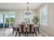 Well-lit dining room with a modern chandelier, backyard view, and a six-seat dining table at 5411 Thistle Field Ct, Wesley Chapel, FL 33545