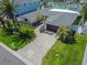 Aerial view of a home with a well-manicured lawn, palm trees, and a brick driveway at 556 Johns Pass Ave, Madeira Beach, FL 33708