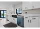 Modern kitchen features white cabinetry, black hardware and faucet, with view of pool and access to outdoor living at 556 Johns Pass Ave, Madeira Beach, FL 33708