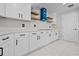 Modern kitchen features white cabinetry, black hardware, door to pantry, and a stylish blue range hood at 556 Johns Pass Ave, Madeira Beach, FL 33708