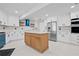 Modern kitchen with white cabinets, stainless steel appliances, center wooden island, and a stylish blue range hood at 556 Johns Pass Ave, Madeira Beach, FL 33708